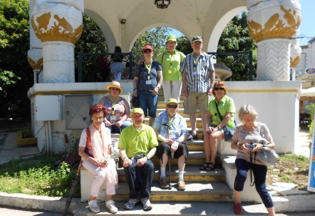Auf diesem Foto sitzt ein Teil der Feriengruppe auf der Treppe eines Sonnenpavillons. Die Sonne scheint und die Farben der Kleidung leuchtet.